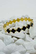 Roman style close bangle in gold with black clover motifs on white stones