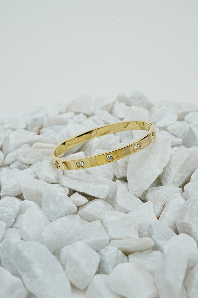 Gold-tone bangle with stone detail on white stones, wide view