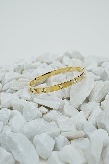 Gold-tone bangle with stone detail on white stones, wide view