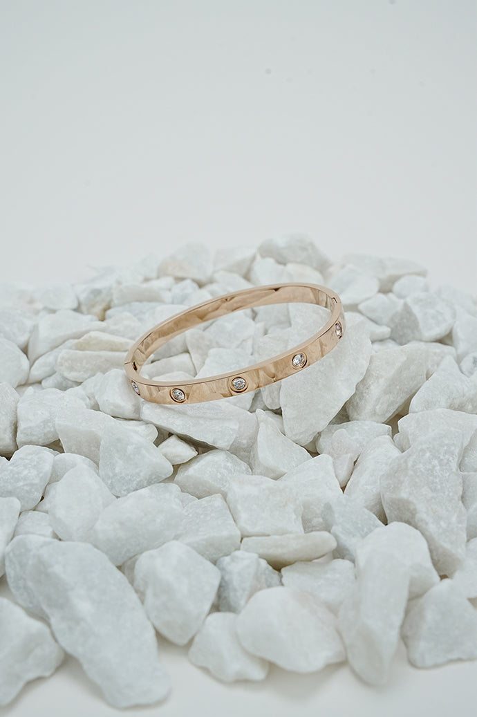 Rose gold-tone bangle with stone detail on white stones, wide view