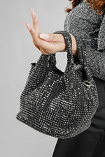 Stellar black crystal bucket bag hanging from the arm, side view