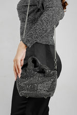Black crystal bucket bag with chain strap worn over the shoulder with a black outfit
