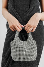 Woman in a black dress holding the Stellar silver crystal bucket bag