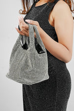 Stellar silver crystal bucket bag held in both hands on a grey background