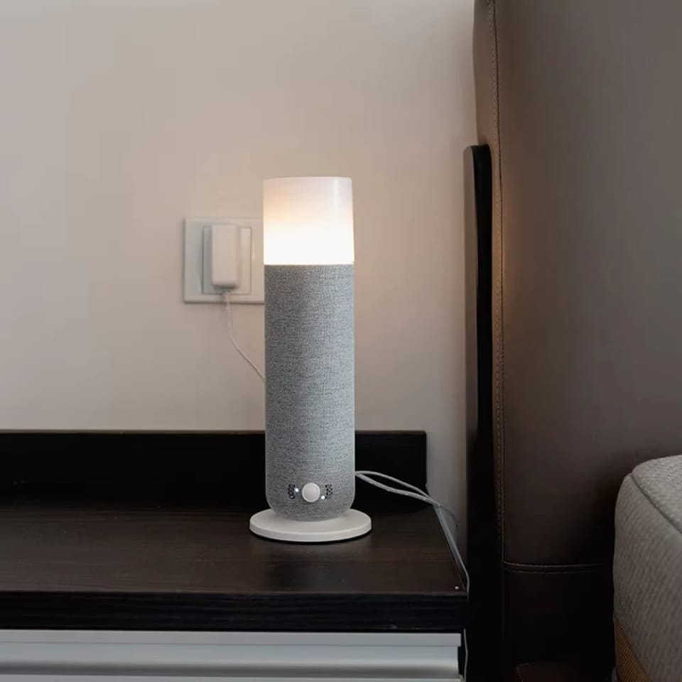 Textured Tower aroma diffuser with warm glow light on a dark bedside table beside a wall socket