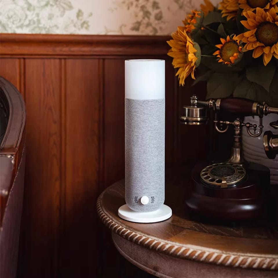 Grey Textured Tower aroma diffuser on a round wooden table beside sunflowers and a vintage phone