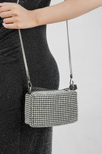 Wang Large silver bag worn crossbody with a black strap, side view